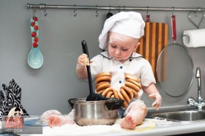 happy cute little baby in a cook cap with a pan